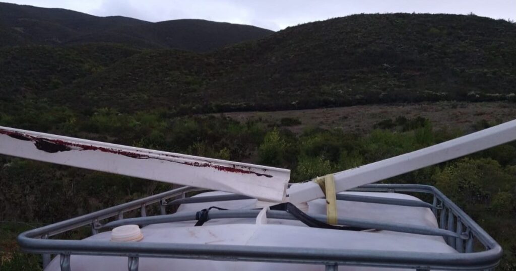 close up of two gutters pointed into a cistern with mountains in the background.