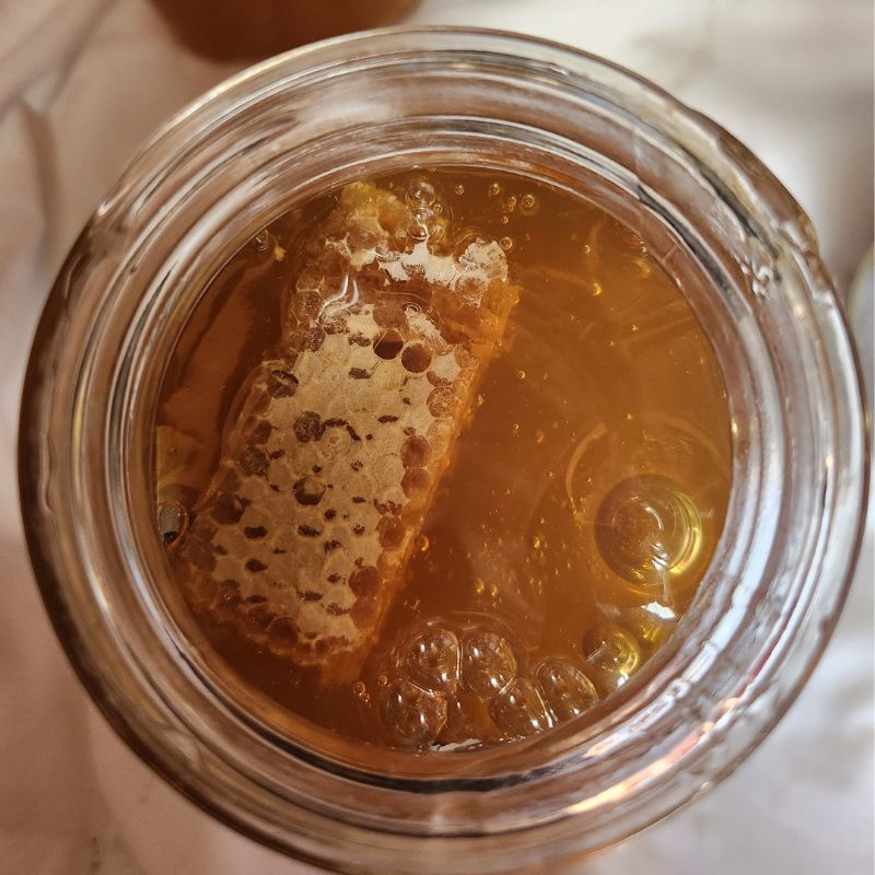 overhead view of open glass jar of infused honey.