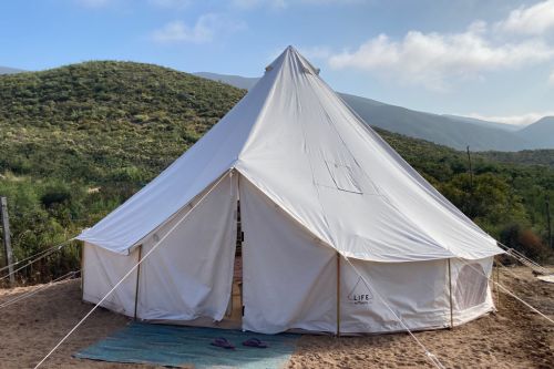 white fabric bell tent with mountains in background.