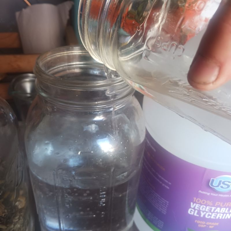 pouring vegetable glycerin into glass mason jar.