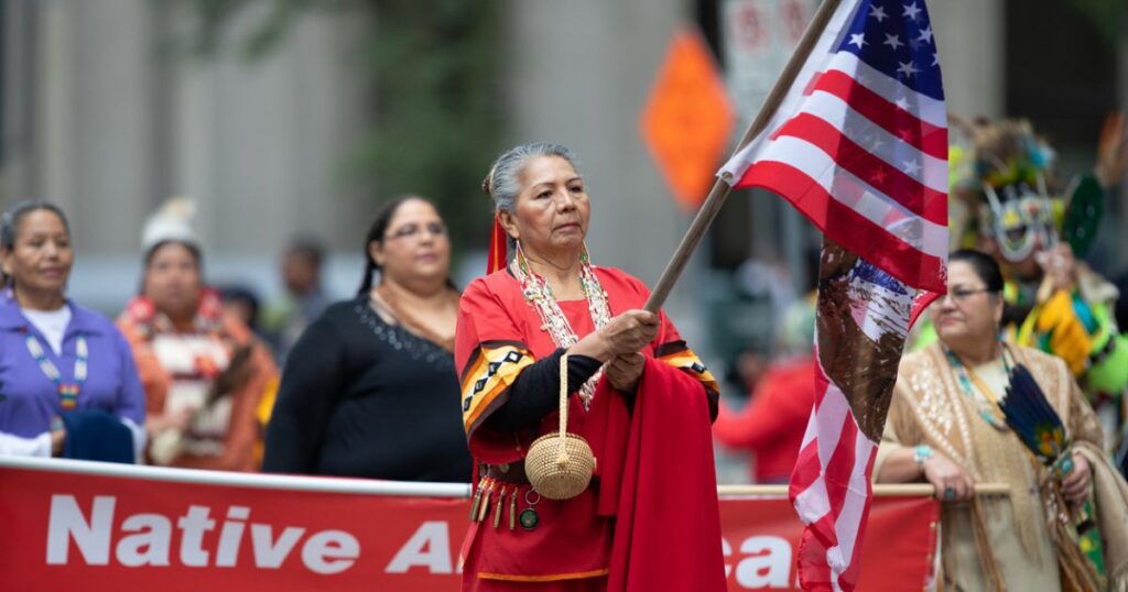 Native American woman in protest holding an American flag.