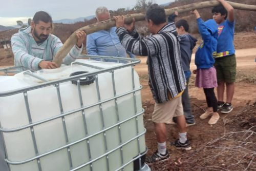 Men and children filling tank with water.