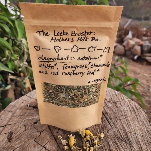 bag of leche booster mothers milk tea on tree stump with chamomile sprinked in front.