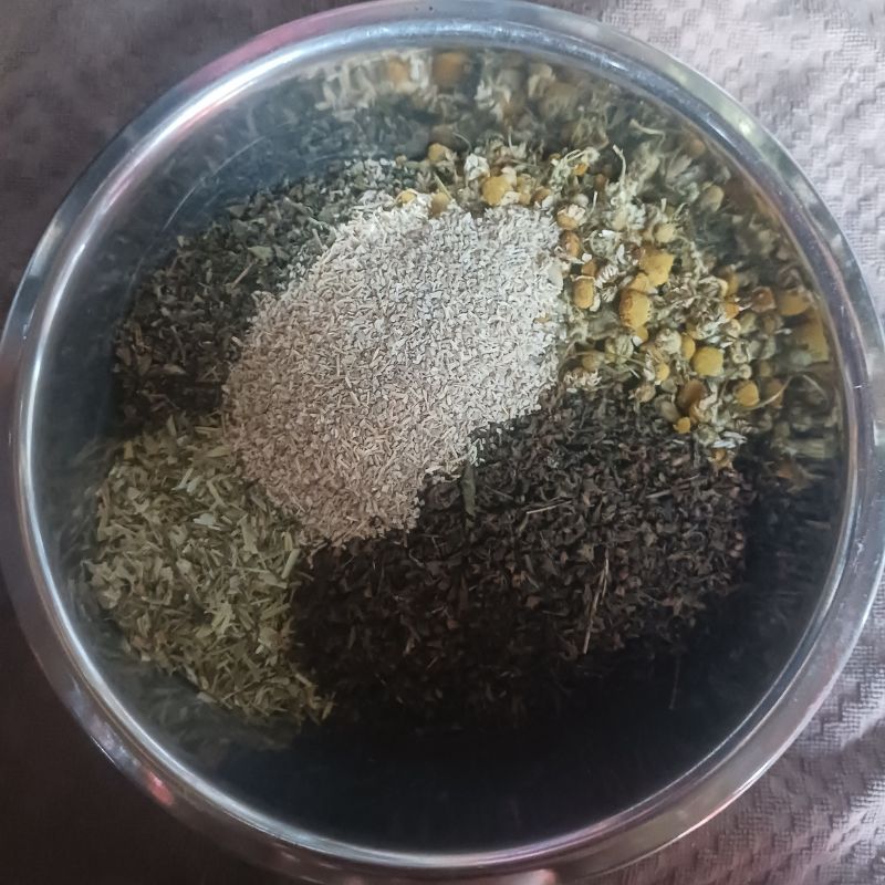 overhead view of multiple herbs in a stainless steel bowl. 