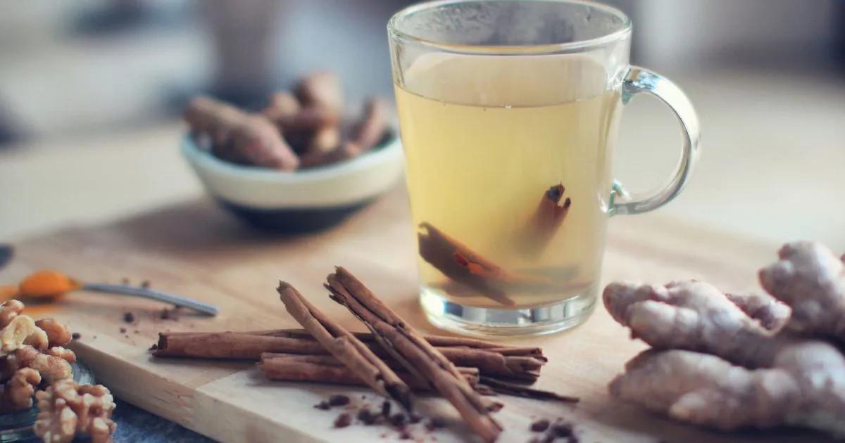 glass of hot tea wikth cinnamon stick on wood table with spices